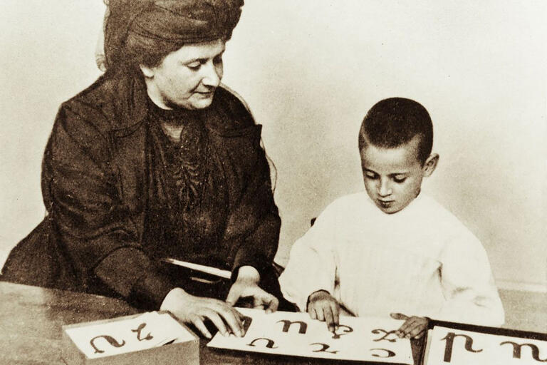 Maria Montessori with boy tracing letters of alphabet