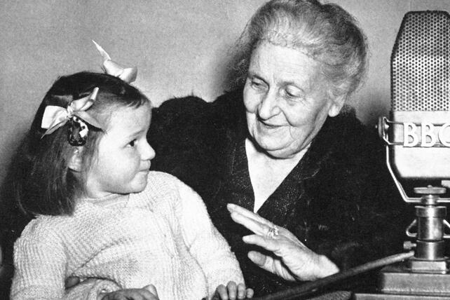 Maria Montessori with girl and BBC microphone in background 